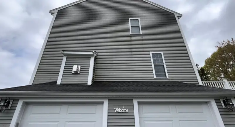 Before: gray vinyl siding on a garage gable with dark mildew streaks below the windows and dormer